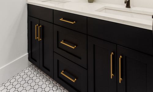 Black bathroom cabinetry with gold/bronze hardware and a white marbled countertop.