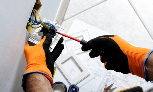 A close-up of a person's hands working on a wiring for an electrical outlet.