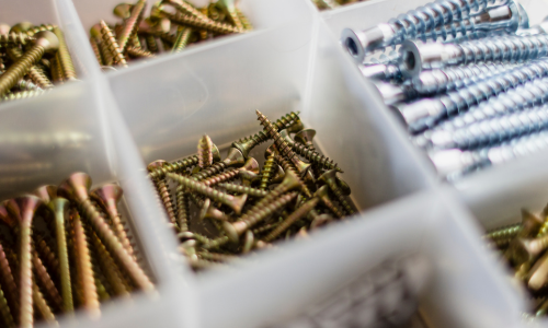 Plastic container with gold, bronze, and silver-colored screws of various sizes.